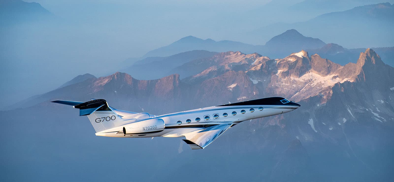 Gulfstream G700 in flight against alpine peaks